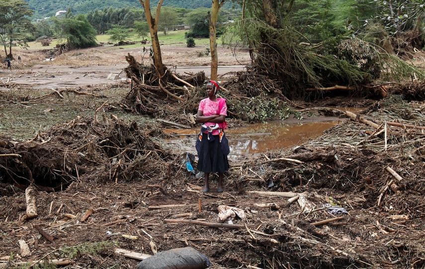 This photo shows a woman standing in the middle of fallen trees and other debris that has happened as a result of flash floods wiped out several homes following heavy rains in Kamuchiri village of Mai Mahiu, Nakuru County, Kenya May 1, 2024.